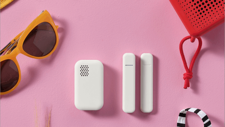 Gula solglasögon, en röd högtalare och tre vita tekniska saker mot en rosa bakgrund