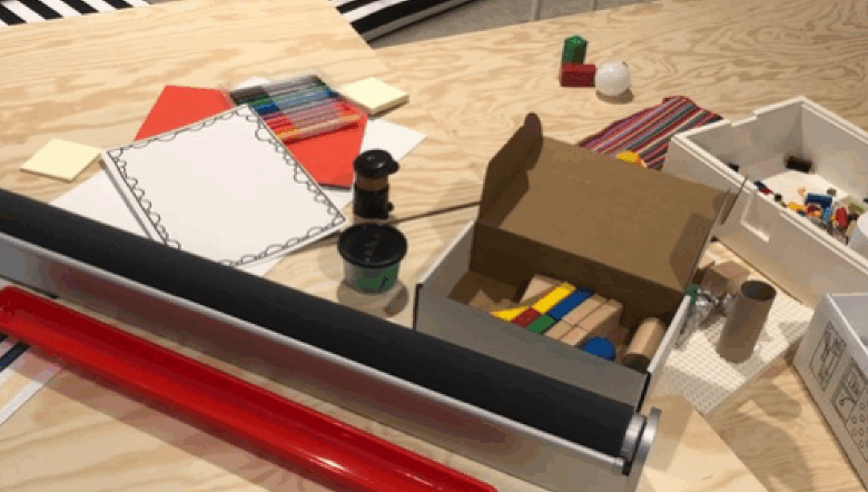 Ett bord i trä med papper, pennor och andra kreativa saker på